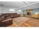 Cozy basement with stone fireplace, brown leather sectional, and neutral patterned rug on hardwood floor at 11077 87Th Ave, Seminole, FL 33772