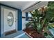 Inviting front porch featuring a decorative front door, lush tropical plants, and a cozy welcome mat at 11077 87Th Ave, Seminole, FL 33772