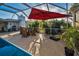 Pool area has a covered lanai with umbrella, a patio table and chairs, and privacy fence at 11077 87Th Ave, Seminole, FL 33772
