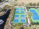 Aerial view of community pickleball and tennis courts, surrounded by lush landscaping and a scenic pond at 11620 Bristol Chase Dr, Tampa, FL 33626