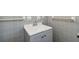 Bathroom vanity with a white sink, gray cabinet, chrome faucet, and towel rack against gray tiled walls at 1290 Michigan Blvd, Dunedin, FL 34698