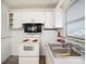 Functional kitchen featuring white cabinets, basic appliances, and a stainless steel sink at 18108 Crooked Ln, Lutz, FL 33548