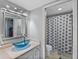 Well-lit bathroom featuring a unique blue glass sink, a mirrored vanity, and a separate toilet and shower area at 19727 Gulf Blvd # 209, Indian Shores, FL 33785