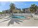 Community pool area with white fencing, lush palm trees, and comfortable lounge chairs at 19727 Gulf Blvd # 209, Indian Shores, FL 33785