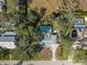 Aerial view of a home with a screened-in pool surrounded by mature trees and adjacent to other properties and the street at 2050 Nigels Dr, Dunedin, FL 34698