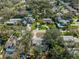 Aerial view of the neighborhood with many houses and in-ground pools surrounded by mature trees on a sunny day at 2050 Nigels Dr, Dunedin, FL 34698