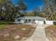 Charming single-story home boasts a well-maintained exterior, a driveway and mature trees at 2050 Nigels Dr, Dunedin, FL 34698
