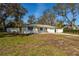 Charming single story home featuring a front lawn, driveway, and white fence, surrounded by mature trees at 2050 Nigels Dr, Dunedin, FL 34698