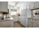 Traditional white kitchen with white appliances, plenty of cabinet space, and views to the outside at 2050 Nigels Dr, Dunedin, FL 34698