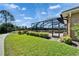 Picture of a backyard view of the green lawn and covered patio from the corner of the home at 412 Arborview Ln, Venice, FL 34292