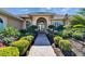 Elegant front entrance with double doors, manicured bushes, and a brick pathway, offering a warm welcome at 412 Arborview Ln, Venice, FL 34292