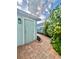 Charming side entrance with a light blue door and a brick walkway surrounded by lush landscaping at 6157 Castleton Hollow Rd, Riverview, FL 33578