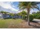 Inviting single-story home with a covered porch, a cozy porch swing, mature palms, and a well-maintained lawn at 10754 111Th N Pl, Largo, FL 33778