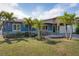 Charming single-story home with mature palms, covered carport, a welcoming porch swing, and manicured lawn at 10754 111Th N Pl, Largo, FL 33778