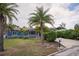 Charming blue single-story home featuring mature palm trees, a lush lawn, and a cozy porch swing for relaxed outdoor living at 10754 111Th N Pl, Largo, FL 33778