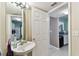 Bathroom featuring a pedestal sink, mirror, and open doorway to a kitchen area with white cabinets at 10814 Brickside Ct, Riverview, FL 33579