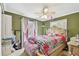 Green bedroom with a large window, ceiling fan, and a decorative bed with floral patterns at 10814 Brickside Ct, Riverview, FL 33579