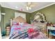 Green bedroom featuring a decorated bed with floral patterns, a ceiling fan, and a vintage dresser at 10814 Brickside Ct, Riverview, FL 33579