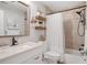 Well-lit bathroom with a marble vanity, decorative shelves, and a shower with a white ruffled curtain at 12162 Aurora Ct, Largo, FL 33774