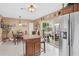 Bright kitchen adjacent dining area, island, stainless refrigerator, and sliding glass doors to covered lanai at 12162 Aurora Ct, Largo, FL 33774