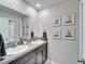 Bathroom featuring double sinks with granite countertop, dark cabinets and a large mirror, adorned with charming artwork at 13006 Tidal Flats Loop, Riverview, FL 33579