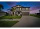The two-story house boasts a dark brown garage door, a well manicured green yard, and a palm tree at 13006 Tidal Flats Loop, Riverview, FL 33579