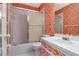Retro bathroom featuring a shower-tub combo, vanity, and orange patterned wallpaper at 1321 N Mcmullen Booth Rd # 1321, Clearwater, FL 33759