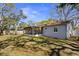 The backyard features a screened in lanai, mature trees, and grassy area at 1582 Sandalwood Dr, Dunedin, FL 34698