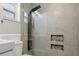 Beautifully renovated shower featuring tiled walls, shower head with integrated shower column, and recessed shelving at 1582 Sandalwood Dr, Dunedin, FL 34698