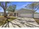 Charming home featuring a red front door, lush landscaping, and a well-maintained front yard at 1582 Sandalwood Dr, Dunedin, FL 34698