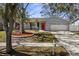 Charming home featuring a red front door, lush landscaping, and a well-maintained lawn at 1582 Sandalwood Dr, Dunedin, FL 34698