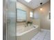 Bathroom with a large tub, shower, and a beach-themed painting above the tub at 1601 E Del Webb Blvd, Sun City Center, FL 33573