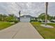 Charming gray home featuring a well-manicured lawn, palm trees, and a long driveway leading to an attached garage at 1604 Azalea Landings Ct, Sun City Center, FL 33573