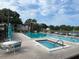 Community pool featuring seating, lounge chairs, and lush landscaping for relaxation and enjoyment at 1725 Pine Ridge E Way # C, Palm Harbor, FL 34684