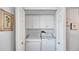 Laundry closet with white cabinets above a stacked washer and dryer unit at 2 Adalia Ave # 803, Tampa, FL 33606