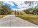 Front exterior view of a home with a long driveway, mature trees, and a well manicured lawn at 22259 Skyview Cir, Brooksville, FL 34602