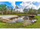 Scenic pond featuring a wooden deck, sandy beach, and local wildlife at 22259 Skyview Cir, Brooksville, FL 34602
