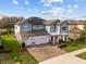 Stately two-story home with a three-car garage, brick driveway, and lush landscaping under a blue sky at 2641 Whittler Br, Odessa, FL 33556