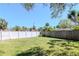 Green backyard with a white fence, lush grass, and mature trees, creating a private outdoor space at 27 Park Ave, Tarpon Springs, FL 34689