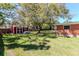 A red storage shed nestled in a spacious backyard with mature trees at 27 Park Ave, Tarpon Springs, FL 34689