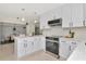 Modern kitchen featuring white cabinets, stainless steel appliances, and stylish pendant lights at 27 Park Ave, Tarpon Springs, FL 34689