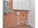 Utility room featuring white cabinetry and a brick wall with plumbing connections at 27 Park Ave, Tarpon Springs, FL 34689