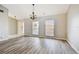 Spacious living room featuring stylish wood flooring, a contemporary chandelier, and bright windows at 3767 Orchard Highlands Dr, Palm Harbor, FL 34684