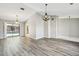 Open living area featuring wood flooring, a stylish chandelier, and sliding glass doors to the pool at 3767 Orchard Highlands Dr, Palm Harbor, FL 34684