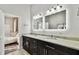 Modern bathroom featuring dual sinks, granite countertops, and illuminated mirrors, complemented by a glimpse into the bedroom at 3844 Wellington Pkwy, Palm Harbor, FL 34685