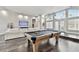 Open living room with a pool table, dark wood floors, and large windows for natural light at 3844 Wellington Pkwy, Palm Harbor, FL 34685
