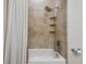 Traditional bathtub and shower combination featuring tiled walls, built-in shelving, and classic fixtures for a cozy feel at 3844 Wellington Pkwy, Palm Harbor, FL 34685