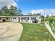 Attractive white home with a large concrete driveway, carport and landscaped front yard at 405 S Lake Dr, Clearwater, FL 33755