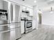 Modern kitchen featuring stainless steel appliances, white cabinetry, and stylish gray wood-look floors at 405 S Lake Dr, Clearwater, FL 33755