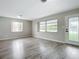 Bright living room featuring wood-look flooring, large windows, and a glass door allowing natural light at 405 S Lake Dr, Clearwater, FL 33755
